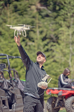 A drone pilot prepares to catch a descending drone quad chopter about to land still in flight.