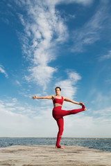 Obraz premium Young woman practicing yoga on the beach