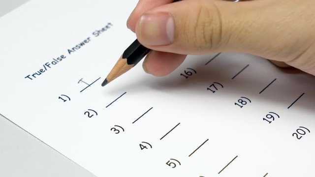 Asian student hand doing examination by write down True and False in standardized test form. Doing classic True and False test.