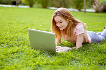 girl on the lawn typing on a laptop