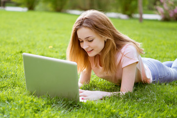 girl on the lawn typing on a laptop