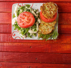 A plate of food on a red wooden table. The view from the top.