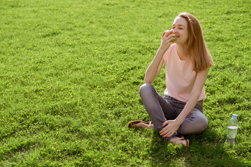 Fototapeta premium girl on the lawn eating an Apple
