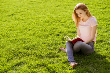 Fototapeta premium girl on the lawn reading a book