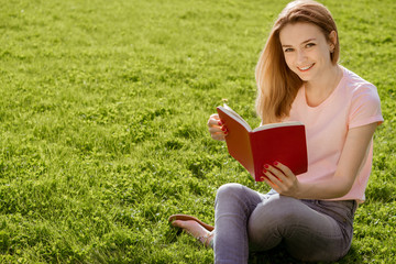 Obraz premium girl on the lawn reading a book