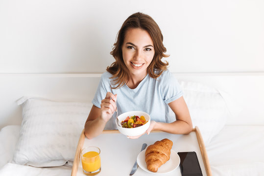 Smiling young woman having healthy breakfast on a tray