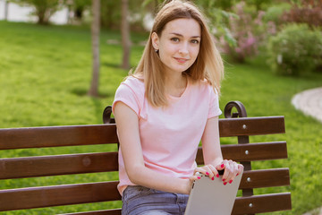 girl with a tablet sitting on a bench in the Park