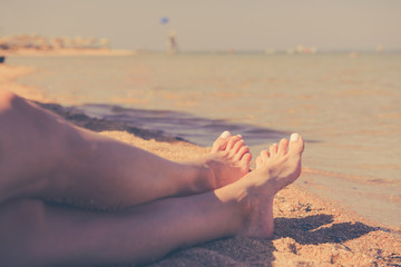 Fototapeta na wymiar young woman legs at sea coast sunset