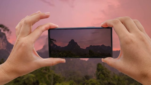 Cinemagraph of Taking Mobile Photo of Limestone Mountain in Khao Sok, Thailand at Pink Sunrise