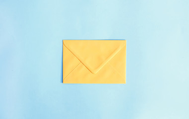 Yellow paper envelope on light blue background. Festive template. Greeting card design. Top view.