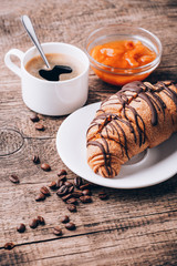 Breakfast with coffee, milk and croissants on wooden table
