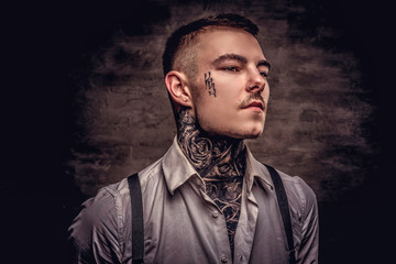 Close-up portrait of a young old-fashioned tattooed guy wearing white shirt and suspenders....