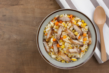 top view of fried rice with pork belly in a ceramic dish on old wooden table. asian homemade style food concept.