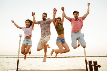 Friends loving couples jumping outdoors on the beach.
