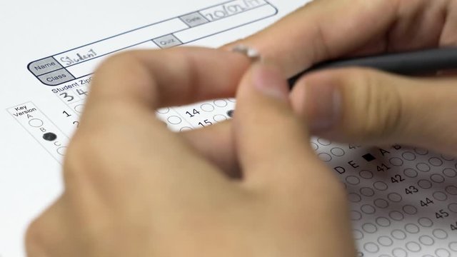 Asian student copying other answer from cheat sheet to cheat on his test.