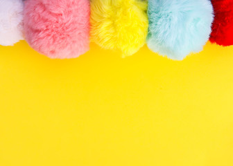 Colorful fluffy pompons on bright background. Fashion decoration festive template.