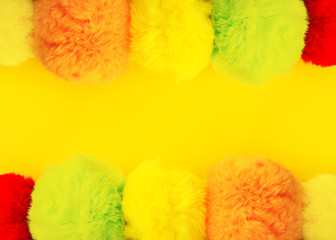 Colorful fluffy pompons on bright background. Fashion decoration festive template.