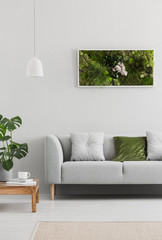 Framed, green moss garden on a white wall in a trendy living room interior with an elegant, gray...