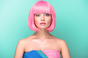 young woman with pink bob cut looking at camera isolated on turquoise