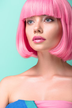 close-up portrait of young woman with pink bob cut looking away isolated on turquoise