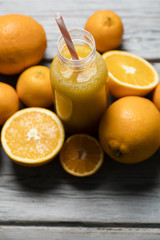 Fresh orange juice in a bottle with oranges on a rustic wooden background