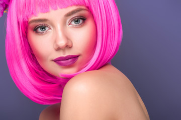 close-up portrait of beautiful young woman with pink bob cut looking at camera isolated on violet