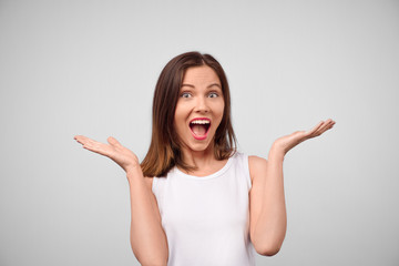 Wow. Beautiful female half-length front portrait isolated on white studio backgroud. Young emotional surprised woman standing with open mouth. Human emotions, facial expression concept