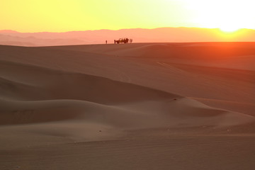Fototapeta na wymiar Gorgeous color layer of sunset over the sand dune of Huacachina desert with the silhouette of dune baggy and people, Ica, Peru 