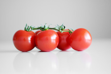 Cherry tomatoes on a branch on a white background close-up.