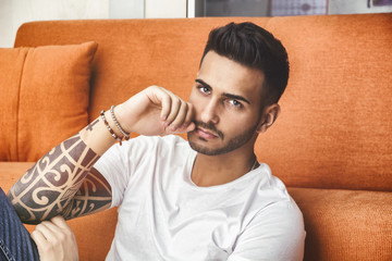 Handsome man sitting on couch looking at camera