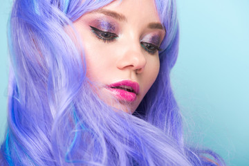 close-up portrait of attractive young woman with curly blue hair isolated on blue