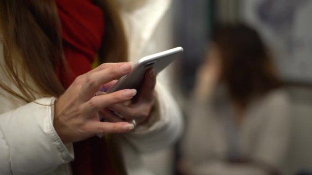 4K, Asian woman using smartphone in subway at Paris. Girl play and touch screen cell phone in metro. Surfing internet, checks social network on her mobile device. Train station platform France-Dan