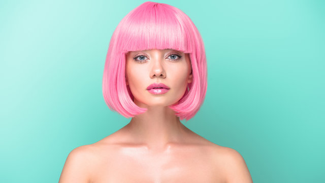 confident young woman with pink bob cut looking at camera isolated on turquoise