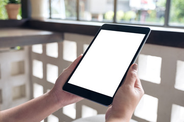 Mockup image of a woman holding black tablet pc with blank white desktop screen in cafe