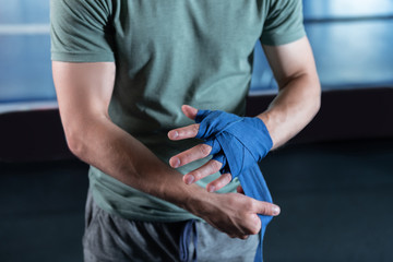Rolling hands. Strong professional muscle man rolling his hands in wrist wraps before training in gym