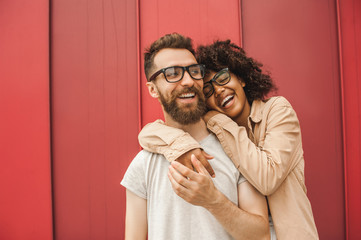 happy young multiethnic couple in eyeglasses hugging on street