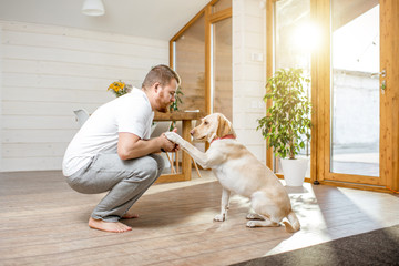 Man playing with the dog giving a paw sitting on the floor in the house