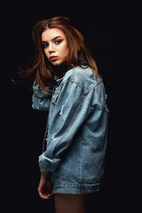 A girl in a denim jacket and short shorts. Posing in the studio on a white background