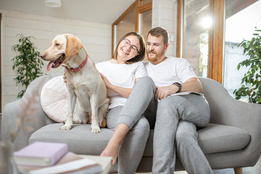 Portrait of a lovely couple sitting with their happy dog on the couch at home