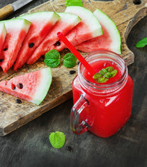Watermelon juice and pieces of watermelon on a dark wooden background, rustic style