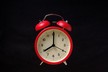 Red vintage alarm clock floating in the dark with blackboard background