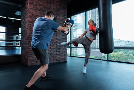 No stress. Athletic blonde-haired woman wearing stylish black and white leggings having no stress while boxing