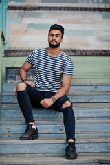 Handsome tall arabian beard man model at stripped shirt posed outdoor. Fashionable arab guy.