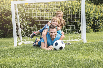 Man with child playing football outside on field