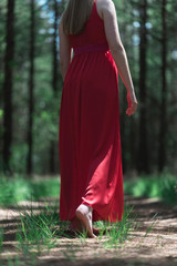 Woman in red dress in bare feet on forest path.