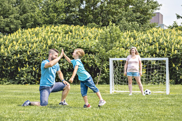 Man with child playing football outside on field