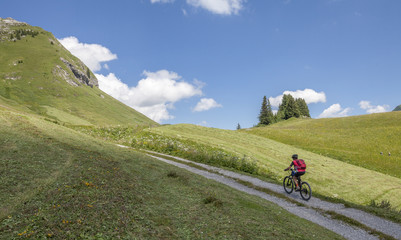 Obraz premium active senior woman, riding her e-mountainbike in the Arlberg area near Lech,Tirol,Austria