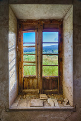 View through an old and broken window showing the mountains in the far distcance