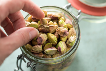 Frau isst Kalifornische, geschälte Pistazien Kerne aus Glas Schale