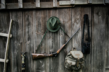 Professionelle Jagdausrüstung für die Jagd. Gewehr, Hut, Tasche und andere auf schwarzem Holzhintergrund.
